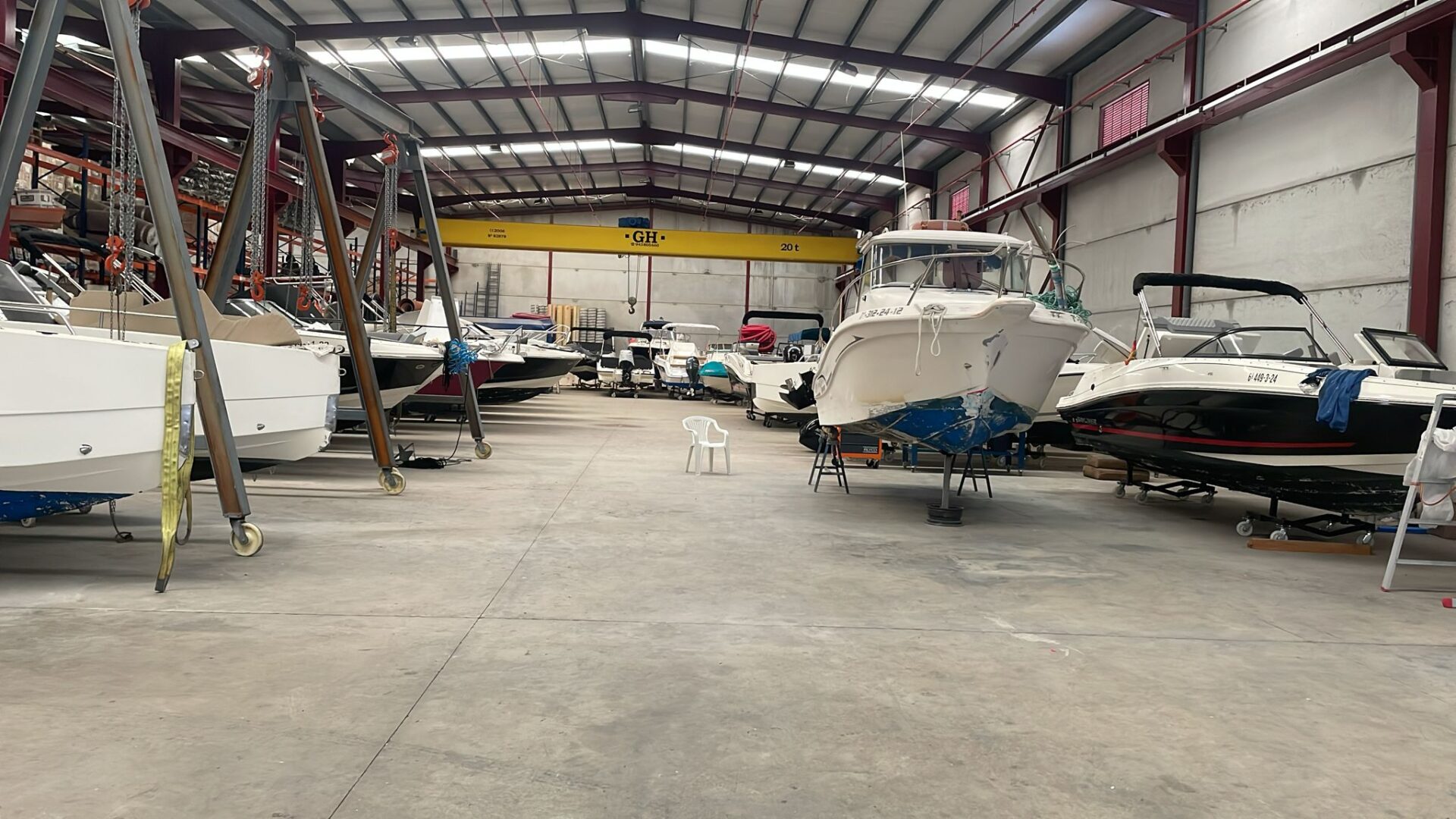 Barcos en nave cerrada de mantenimiento náutico, con embarcaciones sobre soportes y puente grúa interior