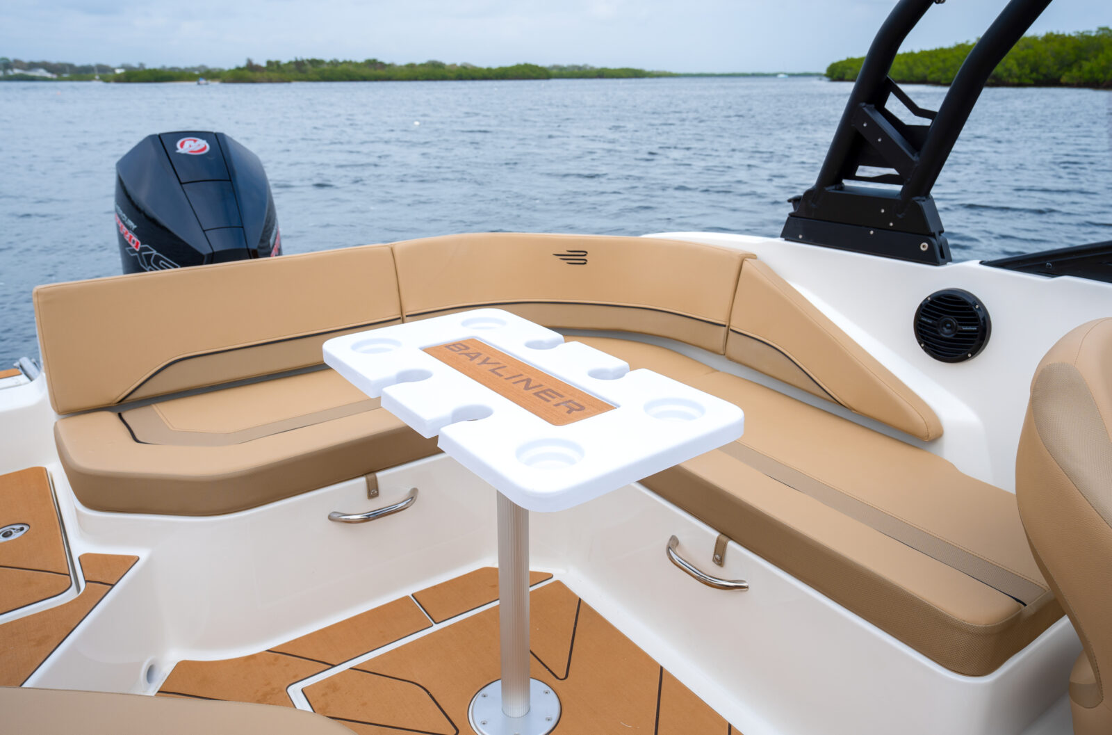 Interior de barco Bayliner con mesa y asientos, vista al mar para alquiler náutico en Huelva.